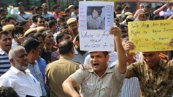 A policeman holding up a placard of Kiran Bedi at the protest outside the police headquarters in ITO | Photo: Suraj Singh Bisht | ThePrint