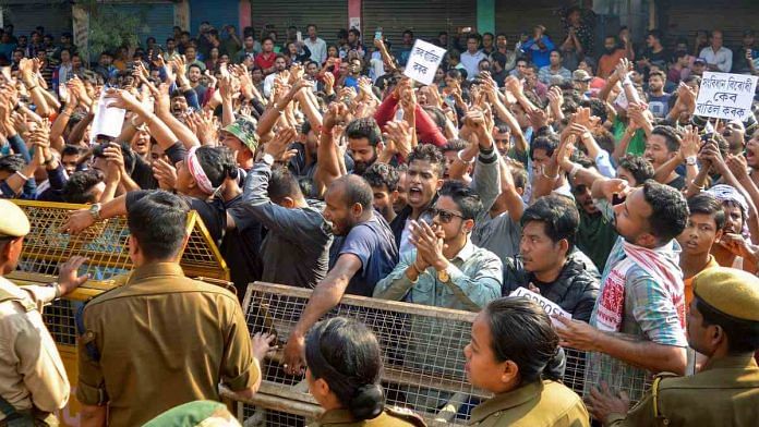 Police personnel stand behind a barricade as they attempt to stop protestors during a bandh over the passing of Citizenship Amendment Bill (CAB) in the Parliament, outside BJP's office at Hengerabari in Guwahati