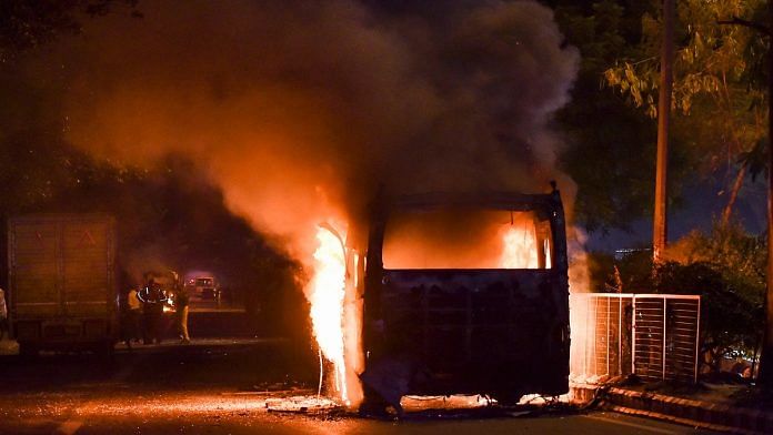 A bus set ablaze by protestors against the Citizenship Amendment Act at Mathura Road, in New Delhi, Sunday. | PTI