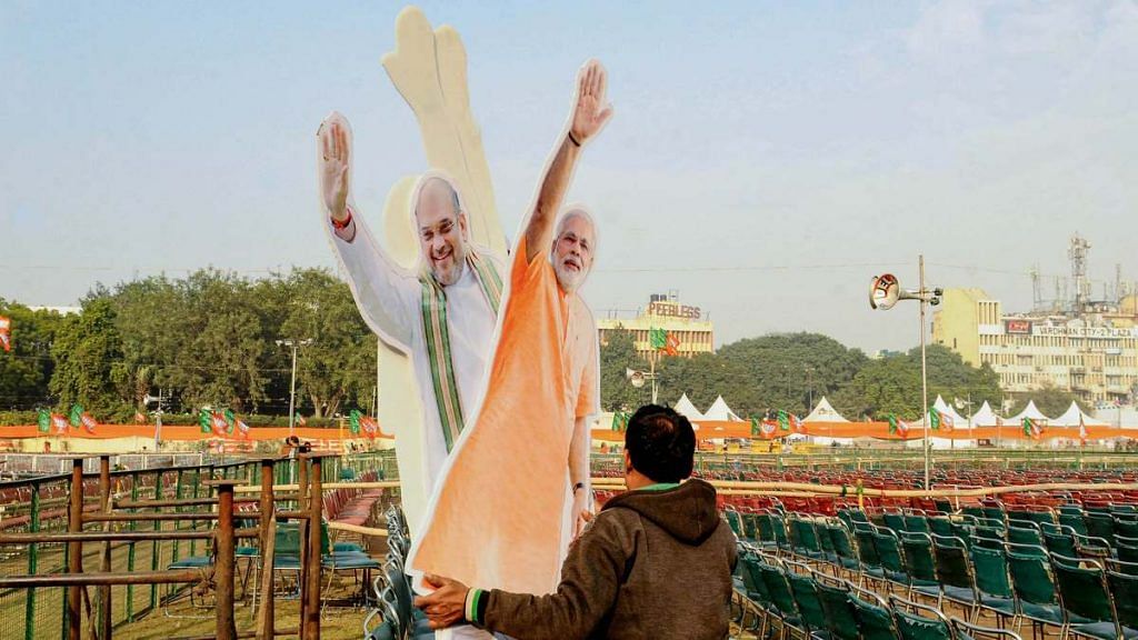 A workers carries cut-outs of Prime Minister Narendra Modi and Union Home Minister Amit Shah at Ramlila Maidan in New Delhi on 21 December