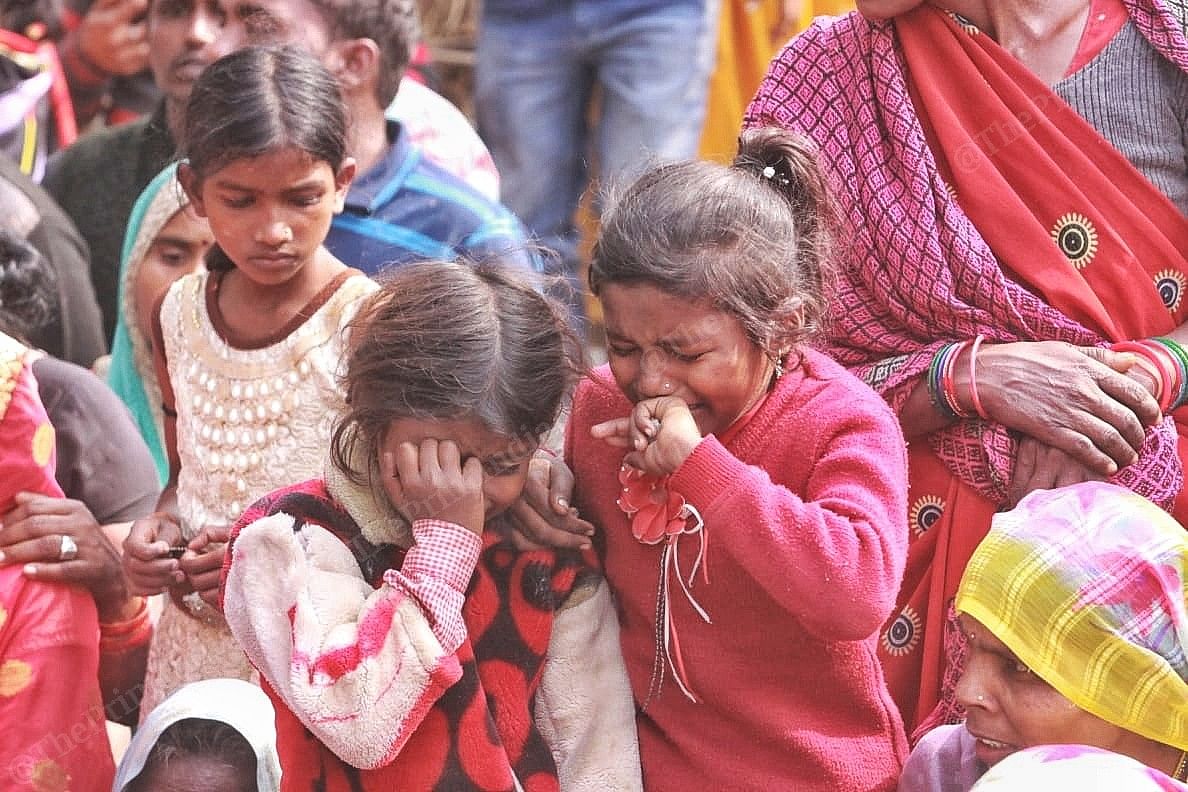 Two young children crying inconsolably at the burial of the victim