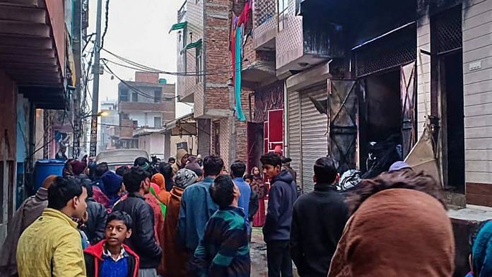 Neighbours stand outside the damaged three-storey residential-cum-commercial building where a fire broke out, in outer Delhis Kirari area | PTI
