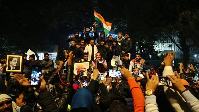Protestors waving the Indian flag and carrying photographs of Dr. B.R. Ambedkar and Mahatma Gandhi