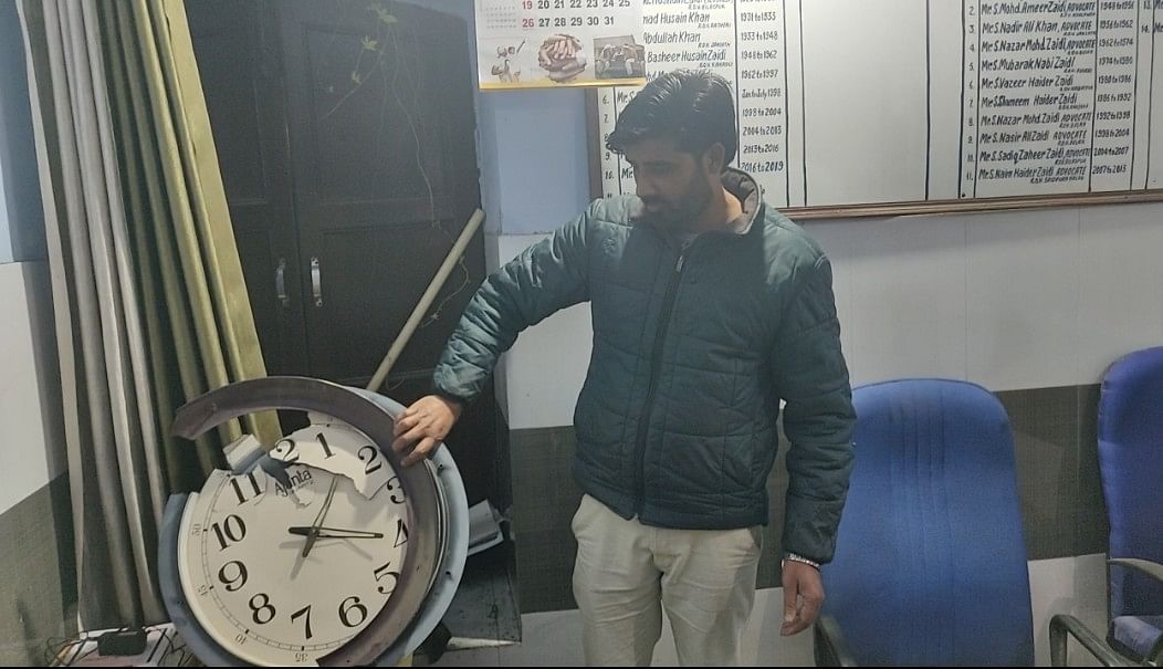 Khurram Ali showing the broken wall clock 