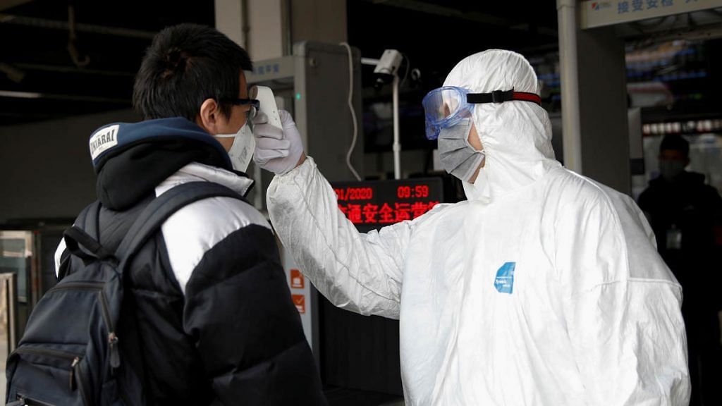 A worker in a protective suit checks the temperature of a man in Beijing. WHO has declared coronavirus outbreak a global health emergency.