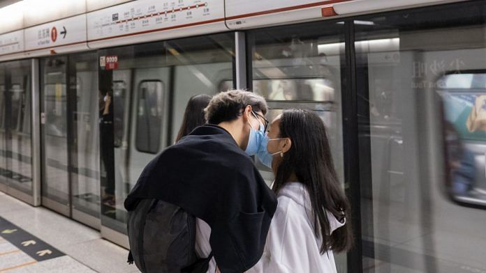 People wearing protective face masks kiss while standing on a platform as a subway train approaches a station, operated by MTR Corp., in Hong Kong, China, on Friday, Feb. 14, 2020. As fears of the novel coronavirus (Covid-19) spread across the region, pharmacies and supermarkets in Hong Kong are running out of basic supplies like toilet paper, paper towels, hand sanitizer and especially masks. Photographer: Justin Chin/Bloomberg