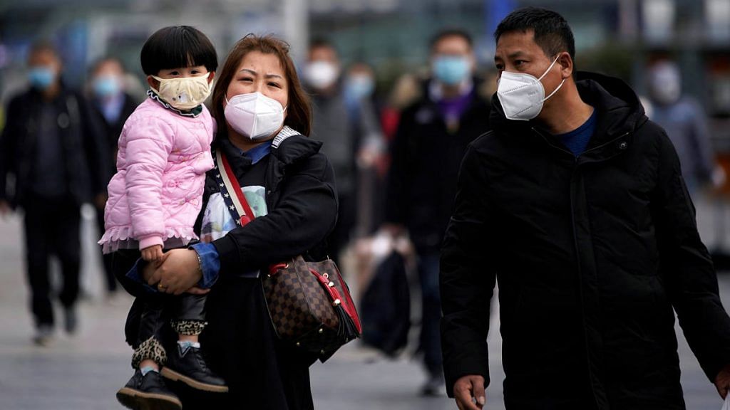 Passengers wearing masks walk outside the Shanghai railway station in Shanghai, China