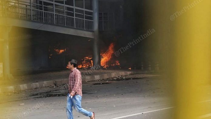 A man walks by a fire burning at a walkway in Northeast Delhi's Gokulpuri on 25 February 2020 | Manisha Mondal | ThePrint