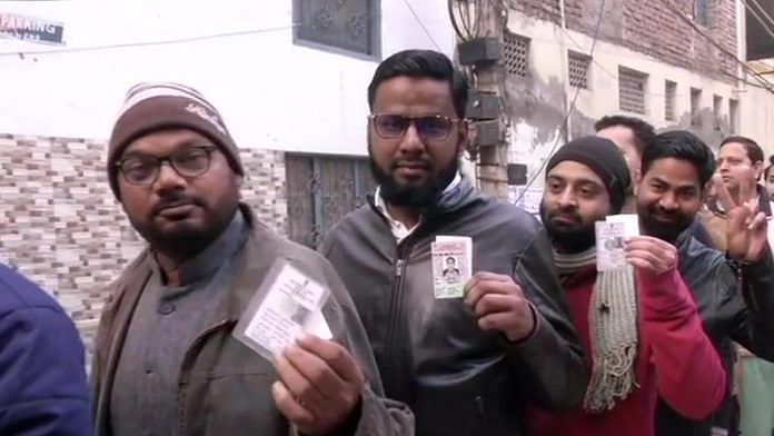 Voters standing in a queue outside a polling booth in Shaheen Bagh