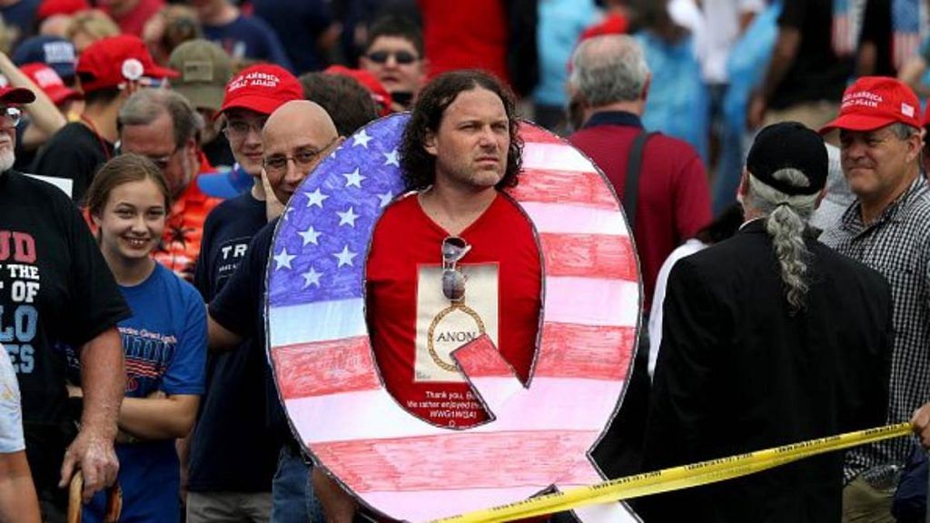 David Reinert holds a large "Q" sign while waiting in line on to see President Donald J. Trump at his rally August 2, 2018. "Q" represents QAnon, a conspiracy theory group that has been seen at recent rallies | Rick Loomis | Getty Images via Bloomberg