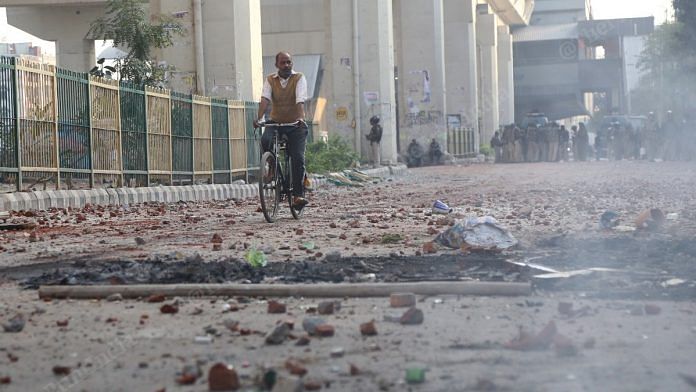 A man cycles past an empty road in Gokulpuri, Delhi, which saw arson and violence during communal riots that broke out in February 2020 | Manisha Mondal | ThePrint File Photo