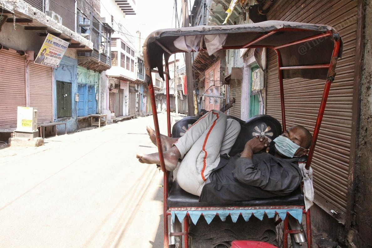 A ricksaw puller sleeps wearing mask | Photo: Praveen Jain | ThePrint