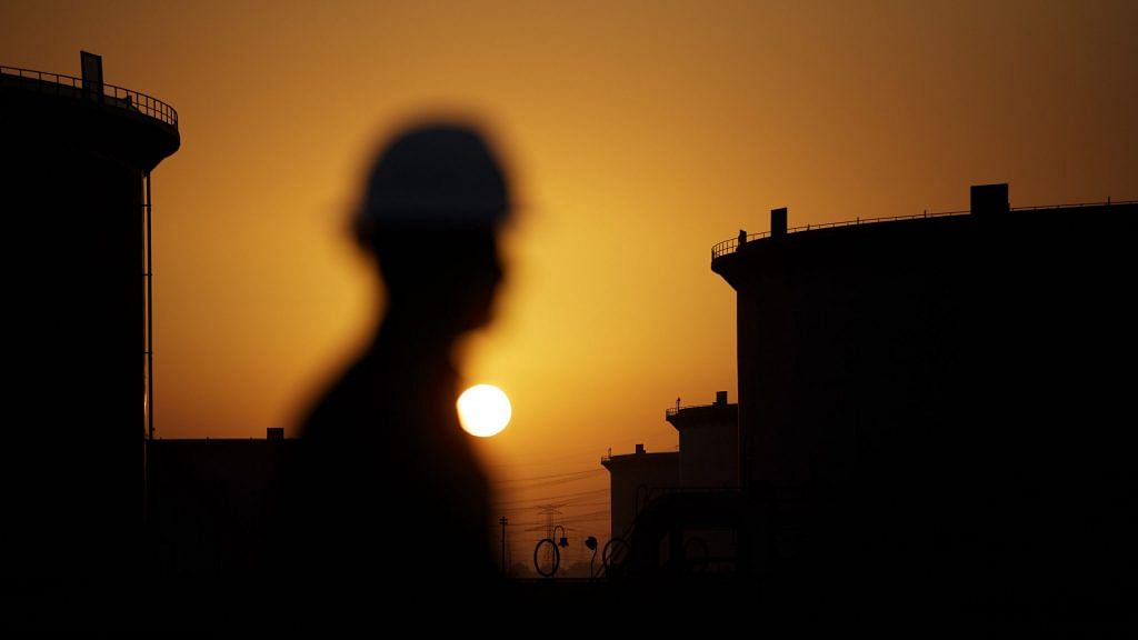 The sun sets beyond crude oil storage tanks at the Juaymah tank farm at Saudi Aramco's Ras Tanura oil refinery and oil terminal in Ras Tanura, Saudi Arabia, on Monday, Oct. 1, 2018. | Photographer: Simon Dawson | Bloomberg