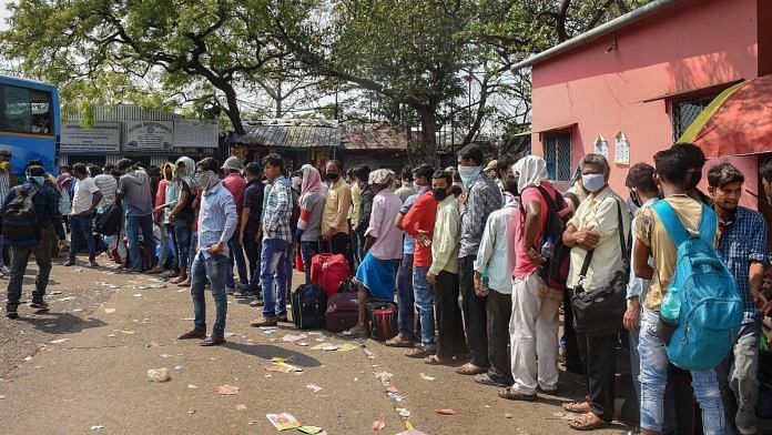 Passengers stand in a queue to board a long-route bus before lockdown in the wake of coronavirus pandemic, in Kolkata on 23 March 2020