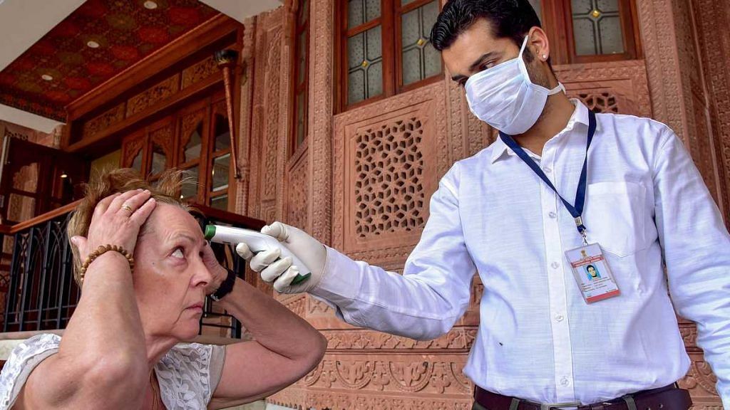A medic checks the temperature of a tourist as part of precautionary screening in the wake of the coronavirus outbreak, at a hotel in Bikaner Thursday