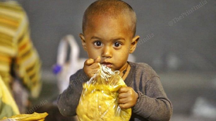 A toddler holding a packet of bread | Photo: Praveen Jain | ThePrint