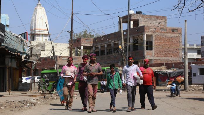 On the empty street of Shiv Vihar people walk covered in Holi colours | Photo: Manisha Mondal | ThePrint