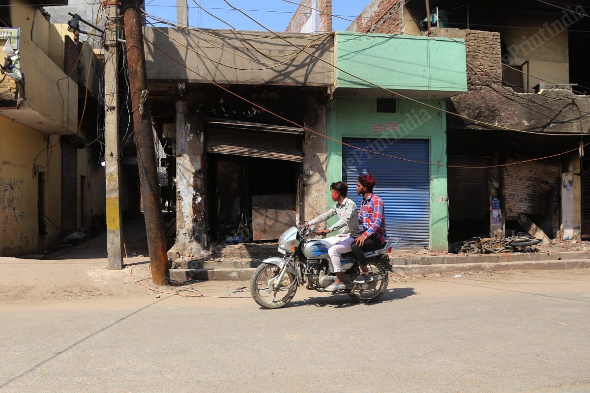 Two men looking at the burnt shops in Shiv Vihar | Photo: Manisha Mondal | ThePrint