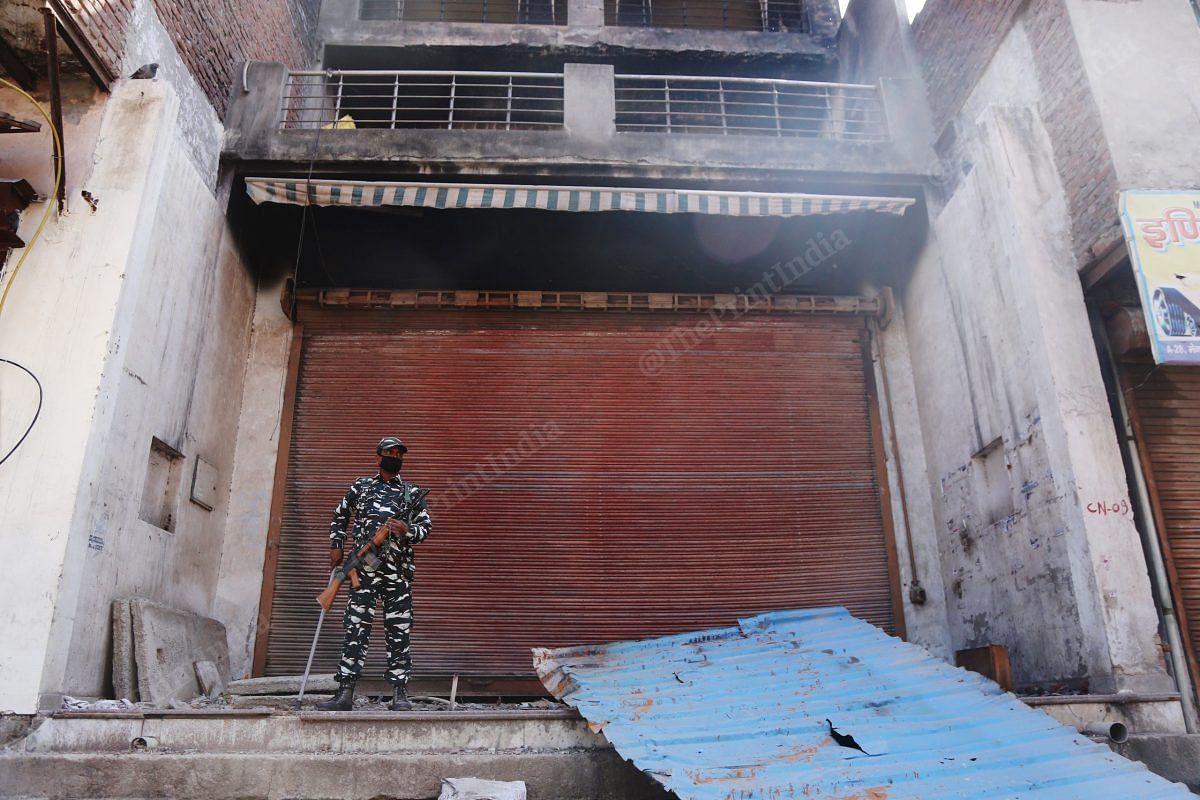 A CRPF officer stands outside a burnt shop in Shiv Vihar | Photo: Manisha Mondal | ThePrint