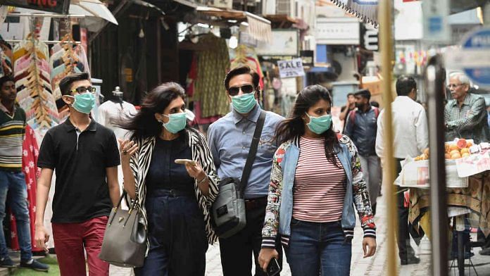 Pedestrians wear protective masks in Khan Market, New Delhi