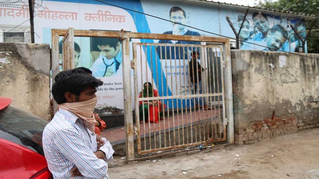 A man waits outside a mohalla clinic in Dakshin Puri