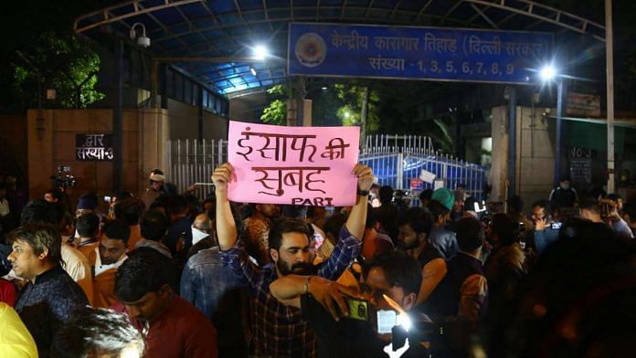 A man holds up a placard in Hindi that reads 'morning of justice', outside Tihar Jail on 20 March 2020 | Suraj Singh Bisht | ThePrint