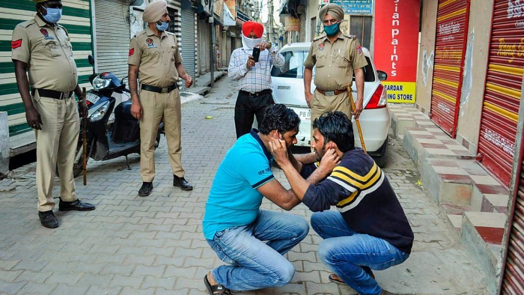 Policemen force two men to do sit ups for flouting the lockdown rules, at Dharampura Bazar in Patiala | PTI