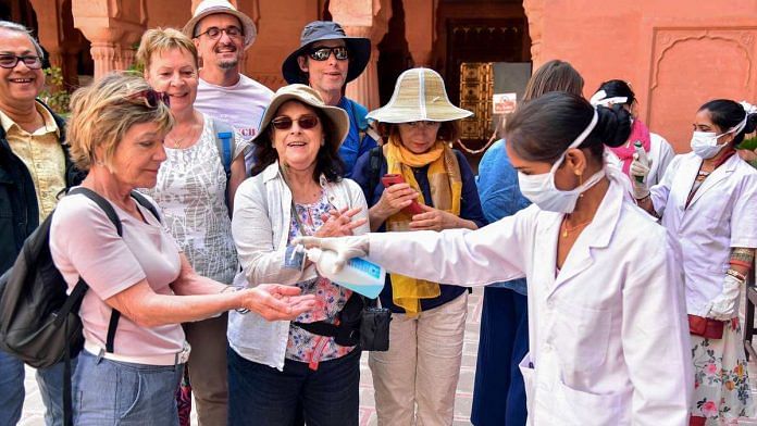 A medic official pumps sanitizer on the hands of tourists at Junagarh Fort in Bikaner on 12 March 2020 | PTI