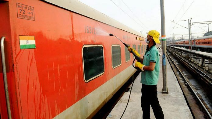 A railway worker sanitises a Rajdhani Express coach (representational image) | Photo: ANI