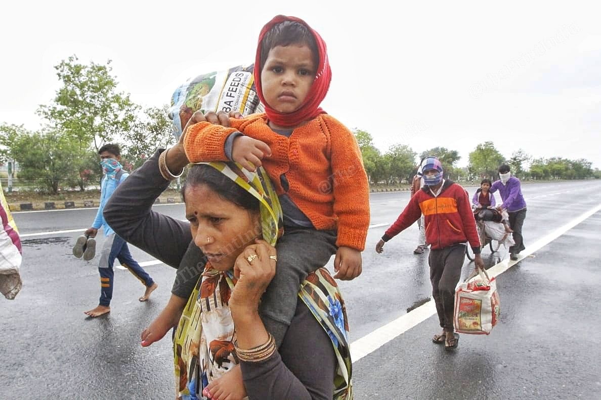 A mother carries her son on her shoulders as she trudges along a damp Delhi-Meerut Expressway | Photo: Suraj Singh Bisht | ThePrint