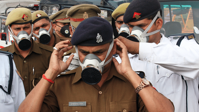 Policemen in Lucknow help each other get their protective masks on