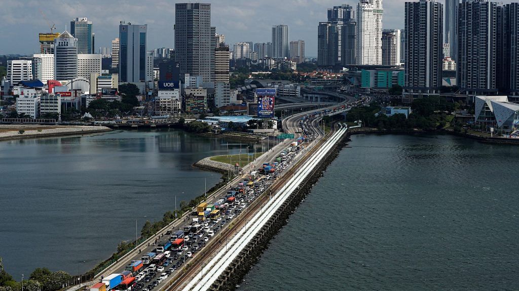 Commuters take the Woodlands Causeway to Singapore from Johor a day before Malaysia imposes a lockdown on travel on 17 March | ANI Photo via Reuters