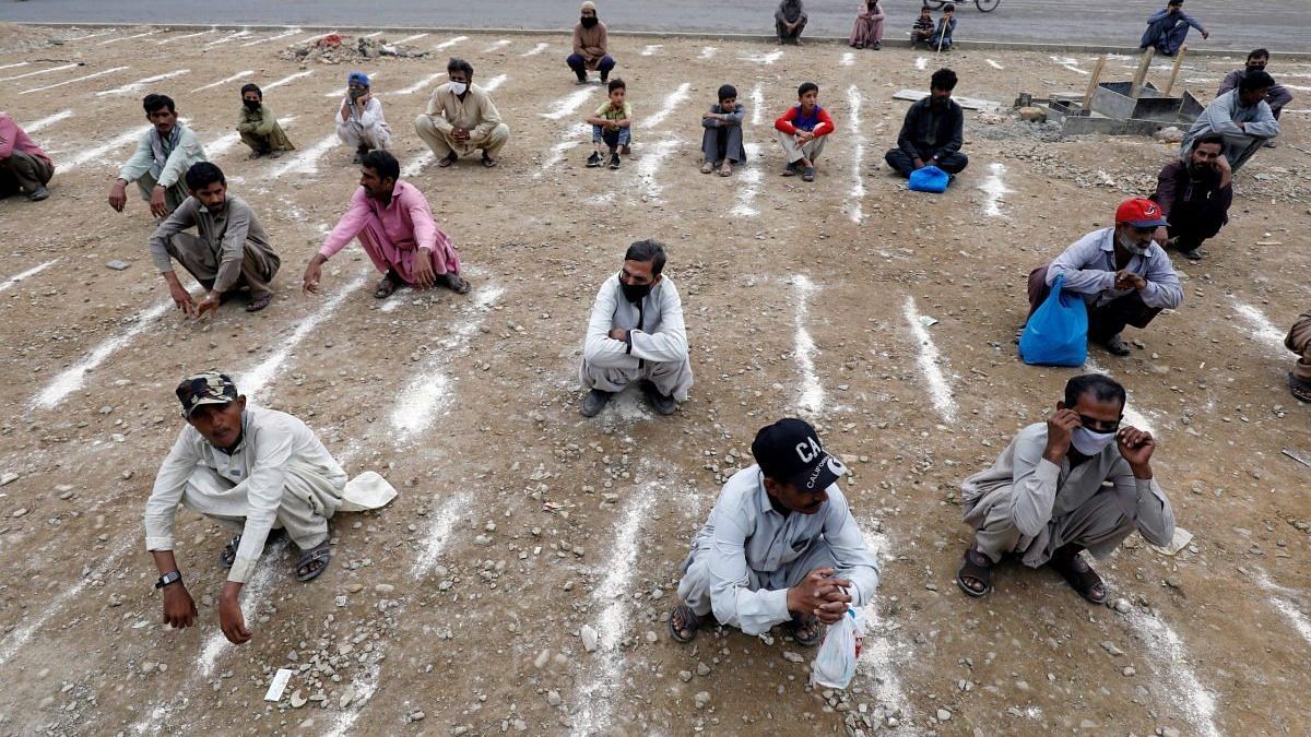 Men sit on the ground with lines drawn with chalk to maintain social distancing during a partial Covid-19 lockdown in Pakistan. Photo | ANI