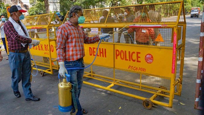 Workers spray disinfectants on a police barricade near Bengali Market, in New Delhi on 9 April 2020
