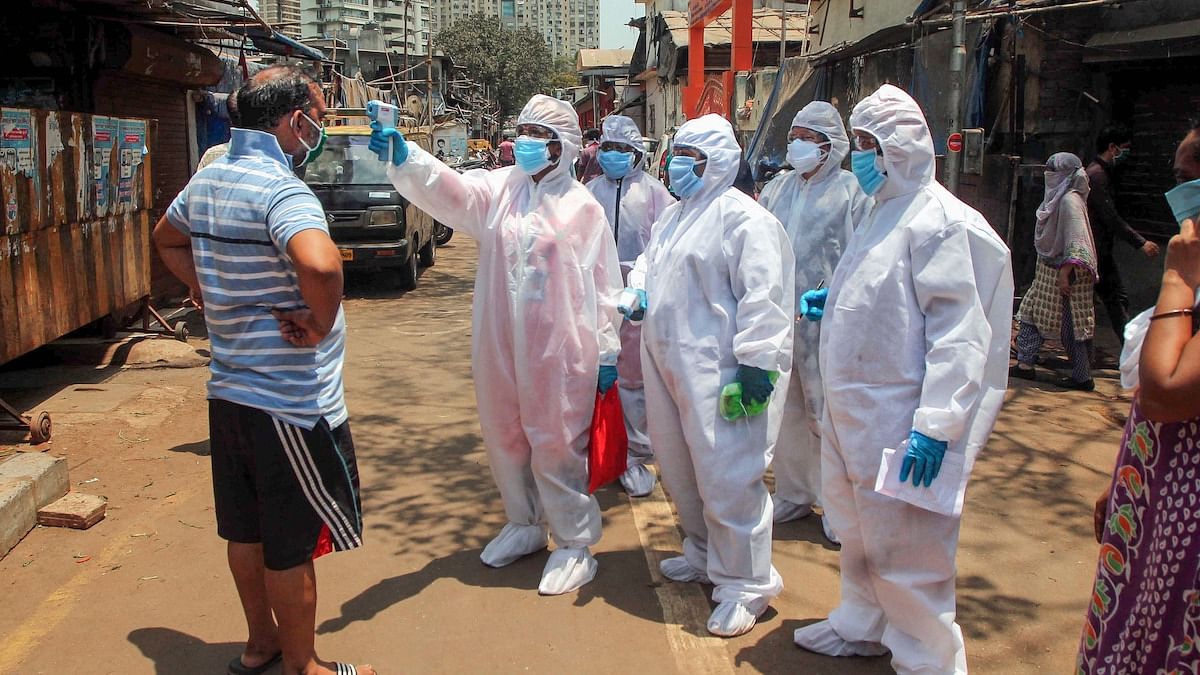 Doctors wearing protective suits check residents with an electronic thermometer inside a slum in Worli, Mumbai | PTI
