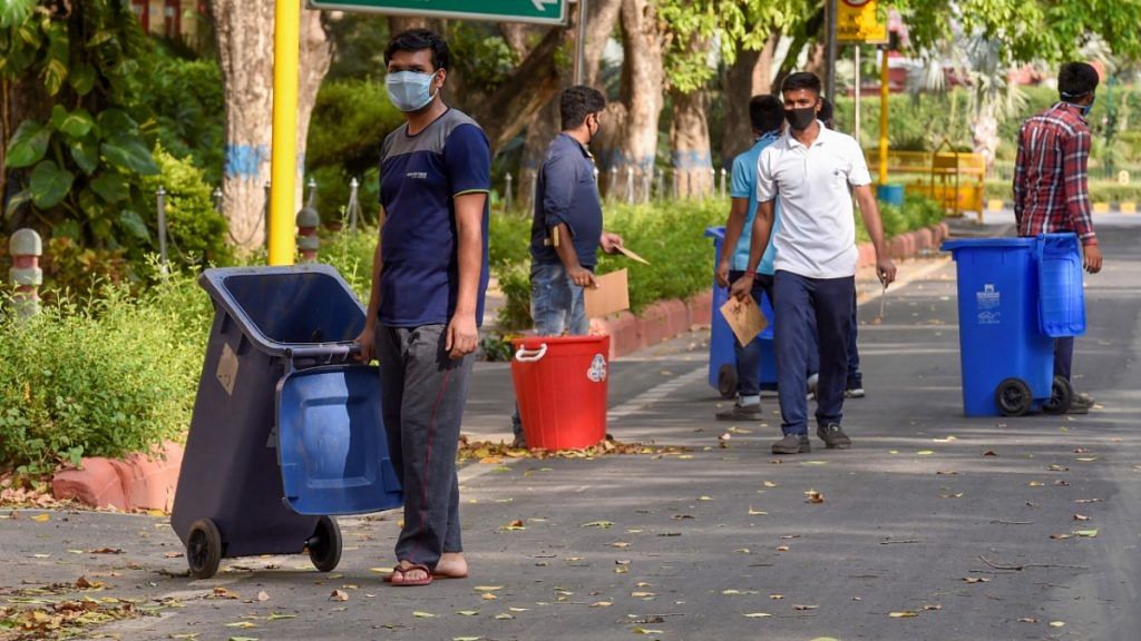 Workers clean a road in central Delhi, during a nationwide lockdown in the wake of coronavirus pandemic, in New Delhi | Atul Yadav | PTI