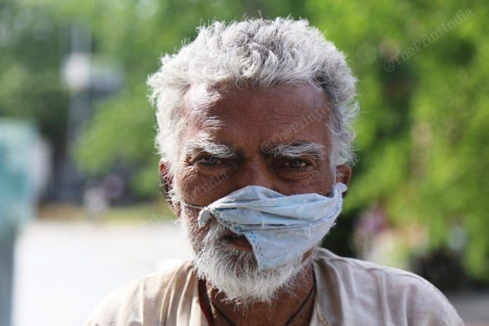 An old man uses a tattered mask to cover his nose and mouth, in New Delhi | Manisha Mondal | ThePrint