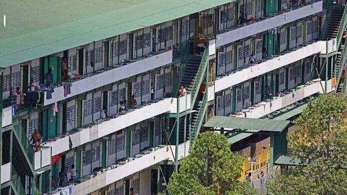 Migrants workers outside their dormitory rooms at Cochrane Lodge II in Singapore on 16 April | Bloomberg