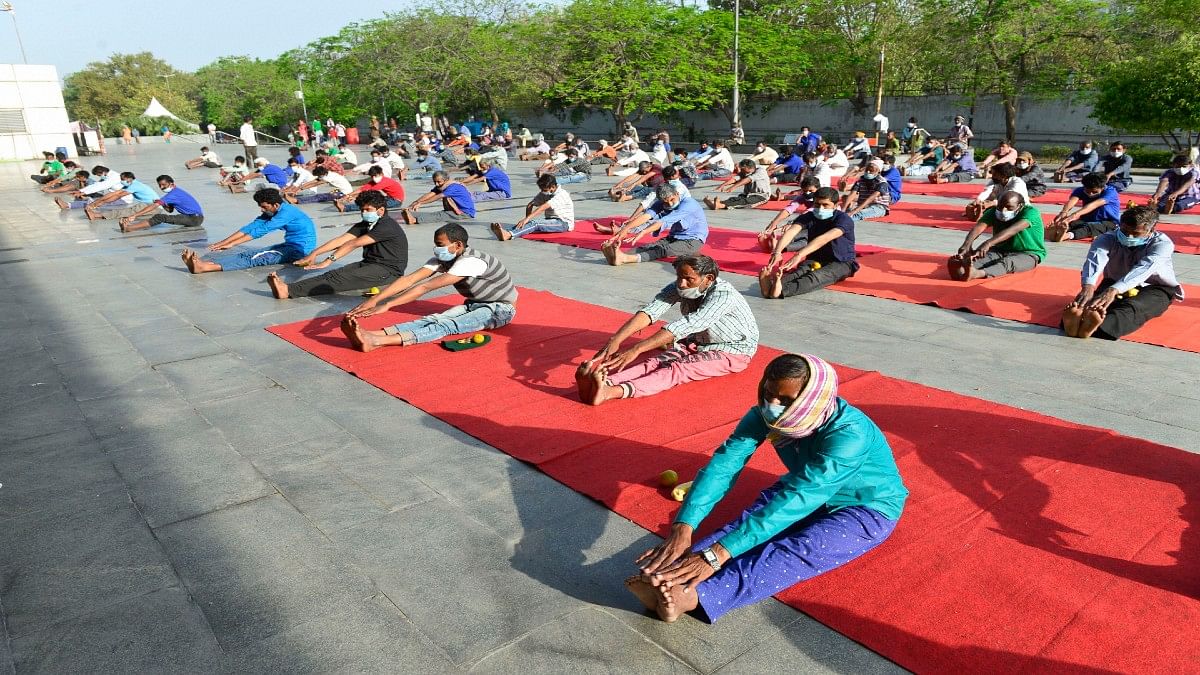 People residing in the makeshift camp at Yamuna sports complex in Delhi perform yoga earlier this week
