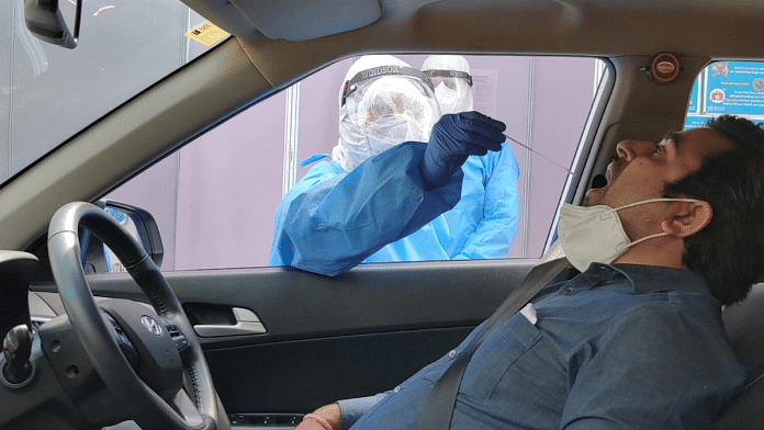 A phlebotomist demonstrates how swab collection is done during a drive-through Covid-19 test, at Delhi's Punjabi Bagh Central Market. | Photo: ThePrint