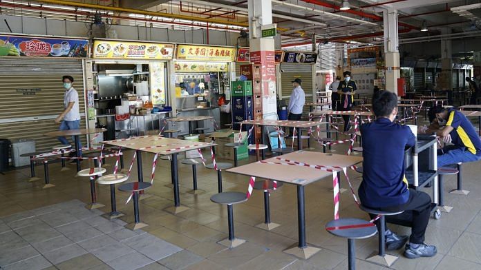 Barrier tapes is wrapped around tables and chairs at a food court during a partial lockdown imposed due to the coronavirus in Singapore. | Bloomberg