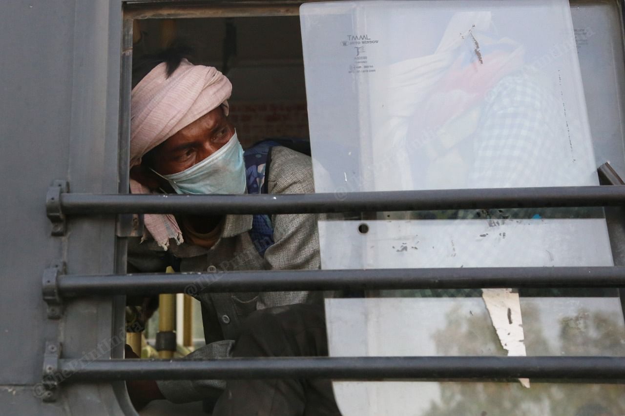 A man looks out the window of a local bus as Delhi Police escorts the homeless to shelter homes. | Photo: Manisha Mondal/ThePrint