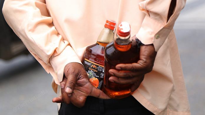A man tucks bottles of alcohol in his trousers in New Delhi | Photo: Manisha Mondal | ThePrint