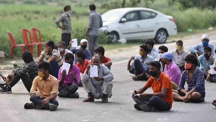 Migrant labourers have been on a quest to get back home. Here, they are seen sitting on the road near the Uttar Pradesh-Bihar border as they wait for their turn to be screened | Suraj Singh Bisht | ThePrint