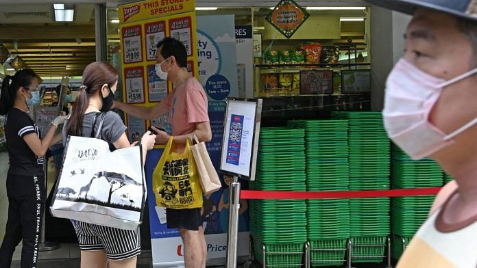 People waiting to enter a supermarket have their identity documents checked by staff before they can enter the premises, as a protective measure against the spread of COVID-19, in Singapore (Representational image) | Photo: Roslan Rahman | Getty Images/AFP via Bloomberg