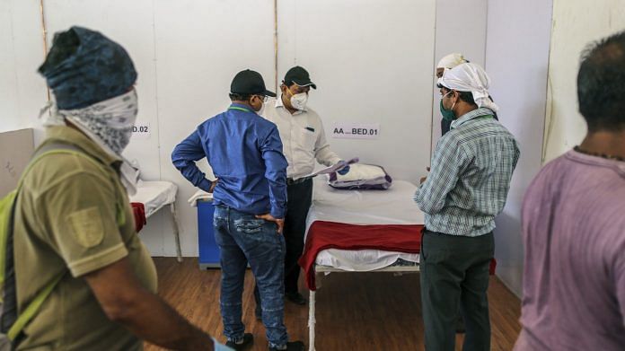 Officials and workers check a plan as the finishing touches are applied to a ward at a dedicated Covid Heath Centre at the Bandra Kurla Complex exhibition ground in Mumbai, India | Bloomberg