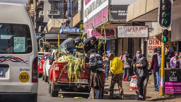 People gather to buy corn from a street vendor in the Central Business District (CBD) of Johannesburg | Photographer: Waldo Swiegers | Bloomberg