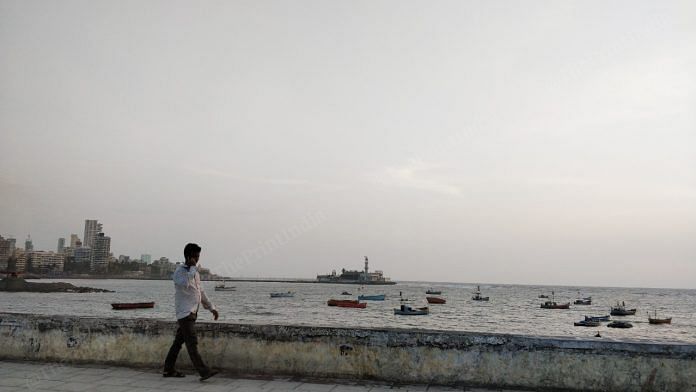 A man walks by on the Cumbaala Hill with the Mumbai skyline and the Haji Ali mosque in the background | Photo: Swagata Yadavar | ThePrint