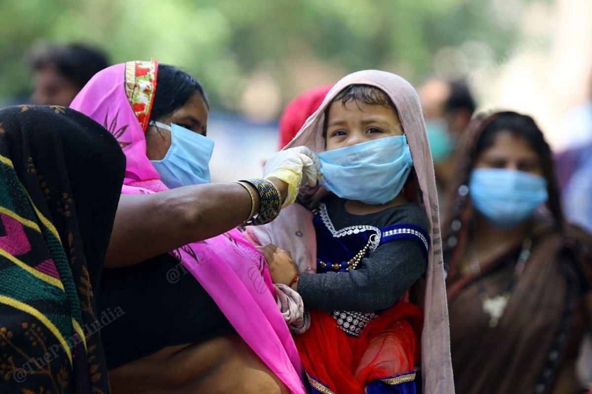 A mother protecting her child by covering her mouth from the mask and save her from coronavirus at the New Delhi railway station| Photo | Suraj Singh Bisht | ThePrint