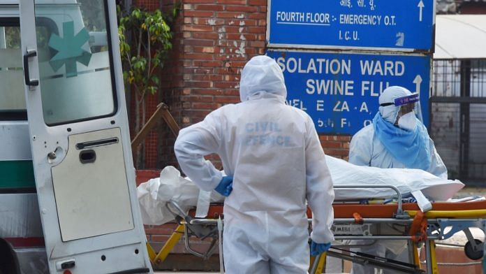 Health workers in protective suits shift a body of a coronavirus victim into a van at LNJP Hospital in New Delhi.| Manvender Vashist | PTI